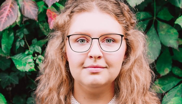 Teenage girl wearing glasses standing in front of plants