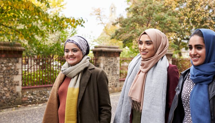Three women wearing headscarves walking in park