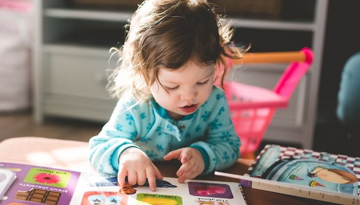 Toddler sat at coffee table reading childrens books