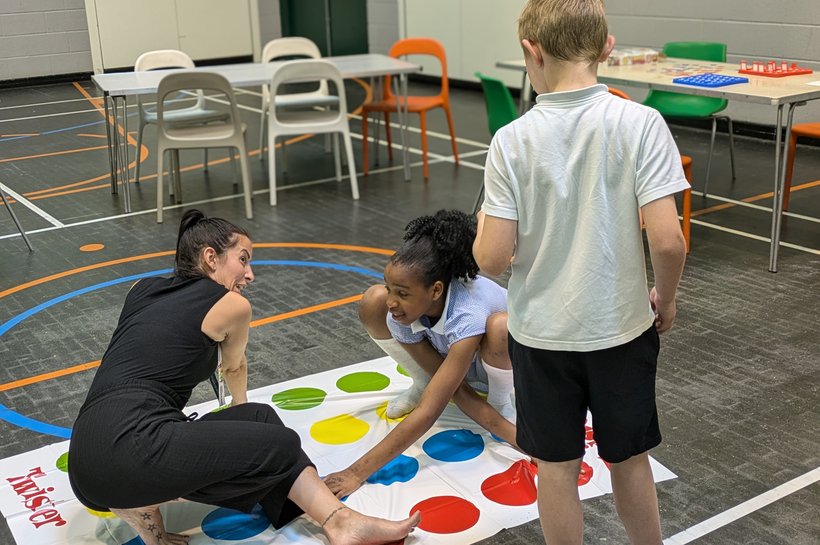Two children and a woman playing twister