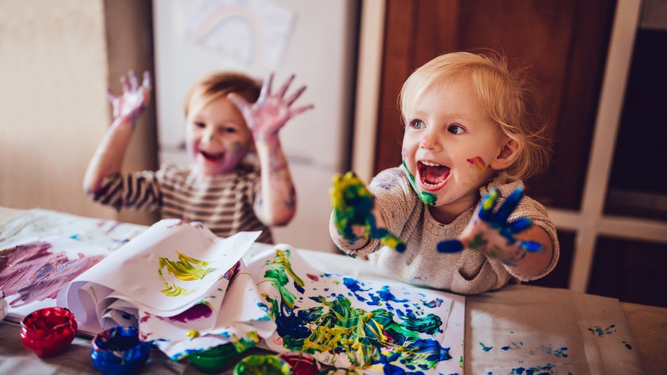 Two young girls painting with hands