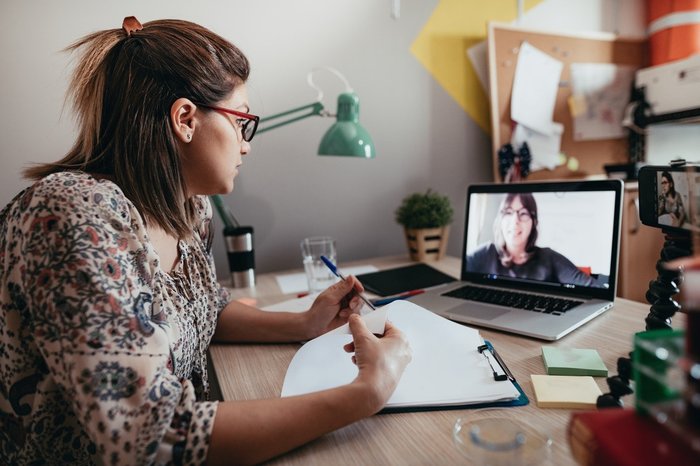 Woman sat at desk talking to another woman on a video call