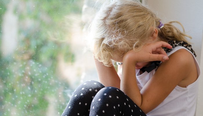 Young  girl sitting by the window and crying