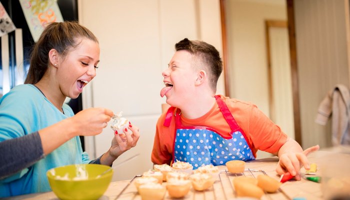 A boy with down syndrome bakes cakes with his sister in the kitchen