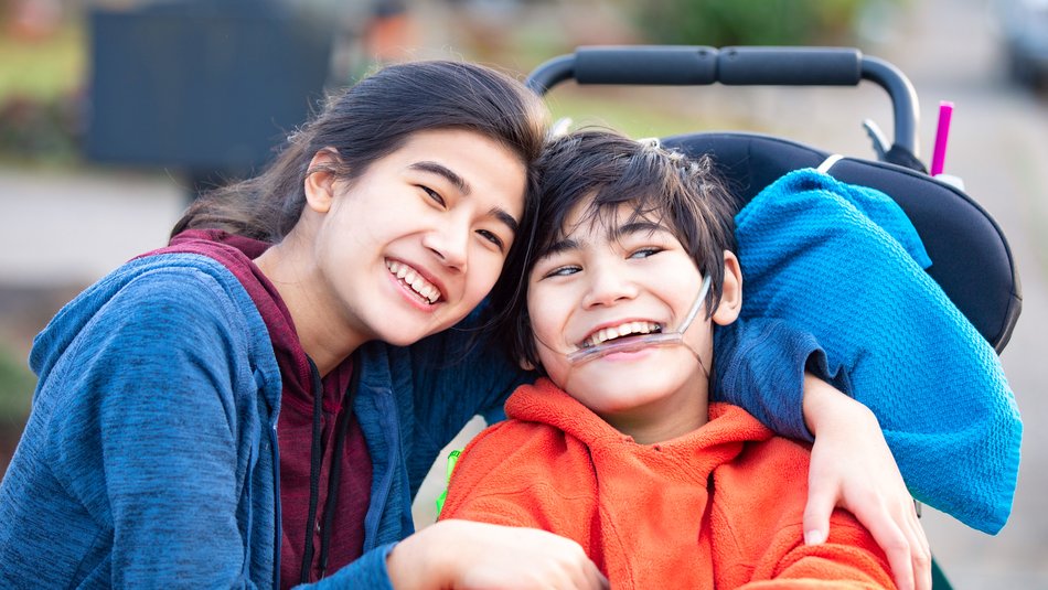 Happy young boy in a wheelchair posing with his sister