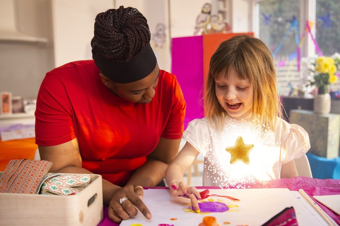 Young girl and support worker doing crafts. Animated gold star is shining on the young girl's chest
