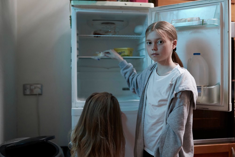 Young girl looking in empty fridge with sister