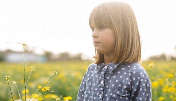 Young girl standing in field of flowers looking worries.jpg