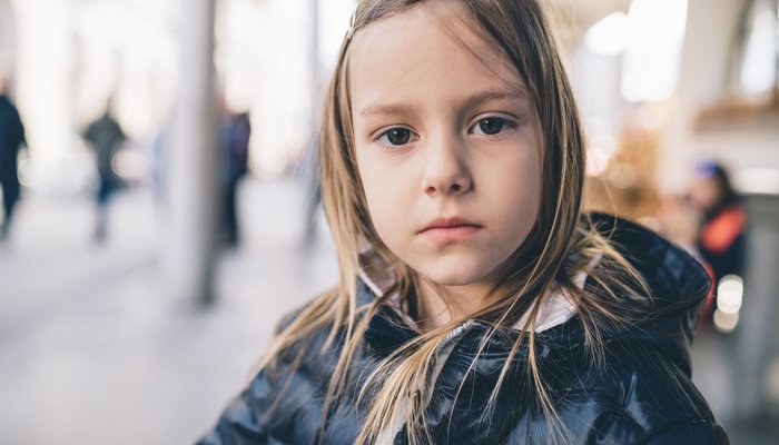 Young girl wearing warm clothing in the city, and is looking at camera with serious expression on her face