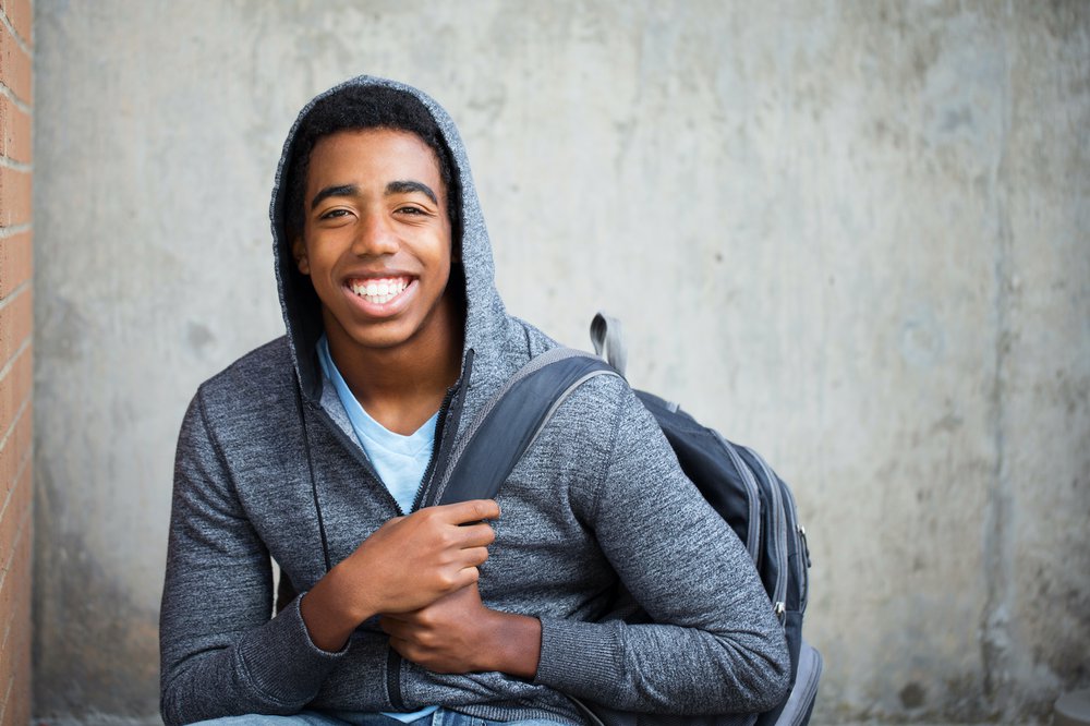 Young teenage boy with big smile wearing backpack and hoodie.jpg