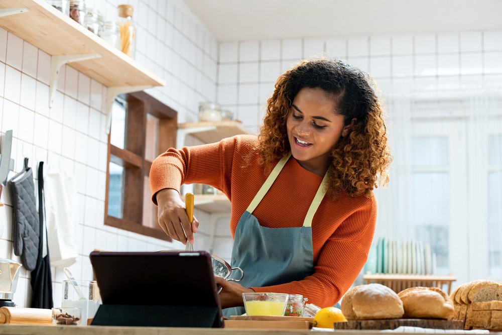 Yung woman in kitchen teaching an online cooking class