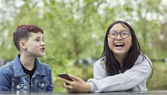 Image of two young people laughing in a park