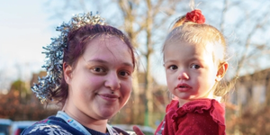 Woman holding little girl wearing a Christmas jumper