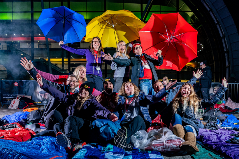Group of people at Byte Night event. They are outside, Smiling and laughing and are surrounded by sleeping bags and umbrellas