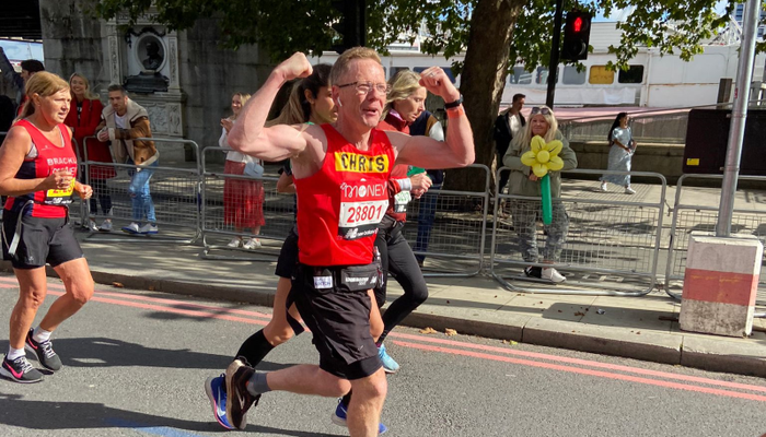 Man running and cheering whilst running the London Marathon for Action for Children