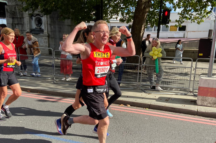 Man running and cheering whilst running the London Marathon for Action for Children