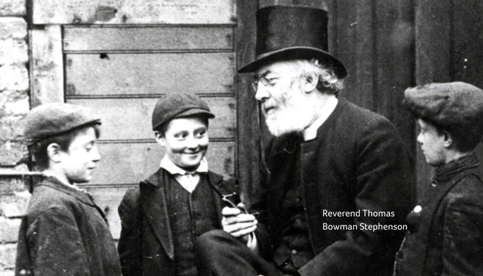 Reverend Dr Thomas Bowman Stephenson talking to three young boys